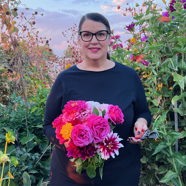 Melynda Fitt standing in her flower field with a handful of colorful blooms